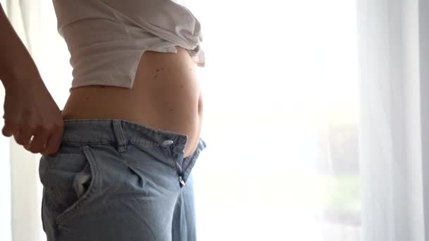 The girl tries to button up jeans. Overweight, full tummy, postpartum recovery psychological problems, weight loss diet concept — Stock Video