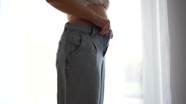 A young girl shakes her belly fat in despair, buttons up her pants. Failed weight loss attempts, depression due to excess weight, postpartum depression — Stock Video