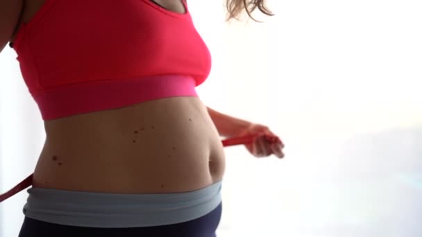 A menina mede a circunferência da cintura com uma fita métrica. Carga esportiva, dieta para perda de peso, recuperação de peso pós-parto — Vídeo de Stock