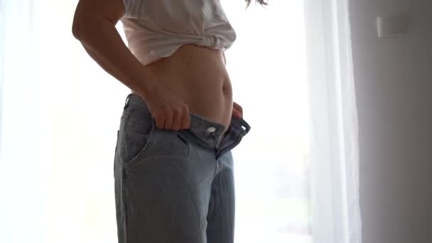 女性はジーンズをボタンアップしようとします。太りすぎ、完全なおなか、産後の回復心理的な問題、減量の食事の概念 — ストック動画