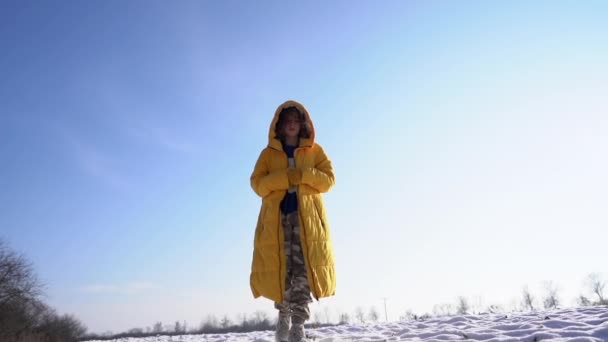 Une jeune femme à la mode vêtue d'un style sportif, chaussure de sport sur ses pieds, marche en toute confiance dans la neige. Fille marche à travers le champ à travers la neige, chaussures de gros plan et la neige — Video