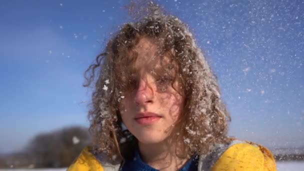 Primer plano retrato de una chica encantadora con el pelo cubierto de nieve. El invierno echa a perder a una joven durante una ventisca — Vídeos de Stock