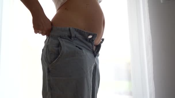 Une femme en gros plan ne peut pas boutonner un jean. Activité sportive pour la perte de poids, problème d'embonpoint, mise en forme du corps — Video