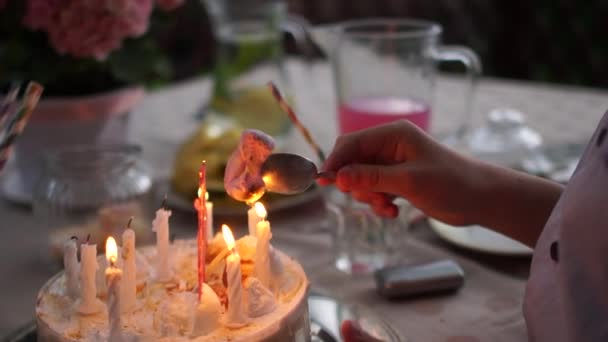 Uma criança entediada acende um marshmallow em um fogo de vela de bolo de aniversário. Childs mãos close-up. Divirta-se, vídeo engraçado, festa de aniversário das crianças — Vídeo de Stock