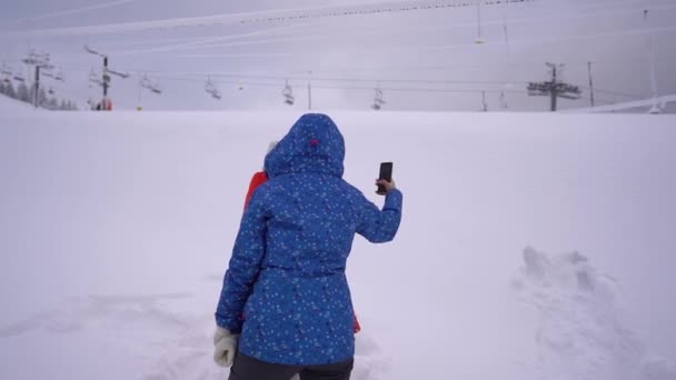 母亲和女儿在一个封闭的滑雪场的背景下自拍。在covid-19封锁期间的滑雪胜地。山里的寒假 — 图库视频影像
