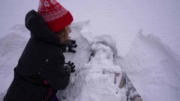 Schneeballschlacht. Winterpaar Mädchen und Jungen spielen im Schnee. Der Junge ist völlig im Schnee verschüttet. Schnee im Gesicht, lustiges Video — Stockvideo