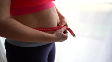 Belini Ölçen Şişman Kadın 'ı kapatın. Ölçüm bandını umutsuzlukla fırlatma, aşırı ağırlık nedeniyle depresyon, doğum sonrası iyileşme