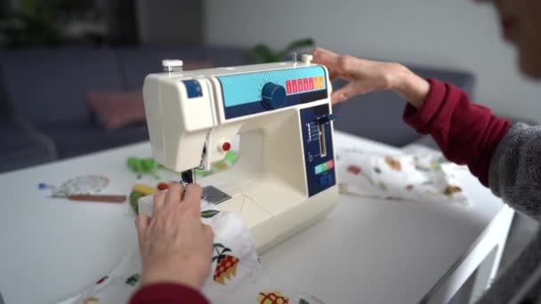 Großaufnahme einer älteren Frau, die mit einer Nähmaschine Textilien näht. Hobby zu Hause, zu Hause bleiben, Gelenkerkrankungen und Arthritis-Konzept — Stockvideo