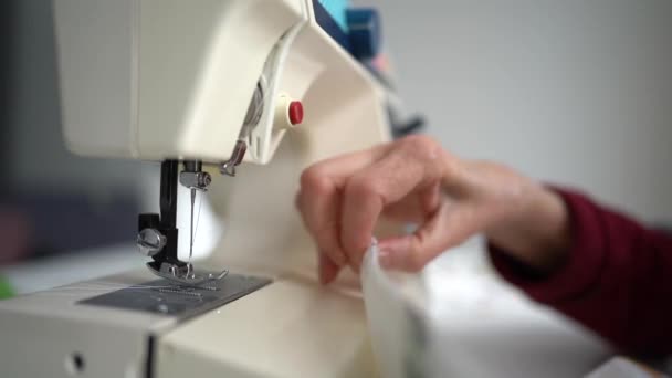 Primo piano di mani di laboriosa donna anziana europea, tessuto di cucitura utilizzando la macchina da cucire presso il suo laboratorio, incentrato sul processo di lavoro. Abbigliamento, Design, sartoria e sartoria — Video Stock