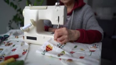 Evde çalış, özürlü kişi. Eklem iltihabından muzdarip yaşlı bir kadının eline yakın plan dikiş makinesi.