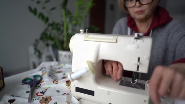 Primer plano retrato de una costurera terminó de coser y está cortando los hilos. Pensionista cose textiles para el hogar — Vídeo de stock