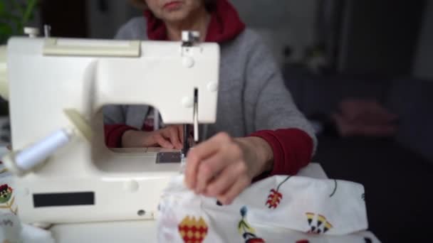 Trabajo en casa para discapacitados. Una anciana con artritis cose en una máquina de coser. Mujer jubilada y su hobby — Vídeo de stock