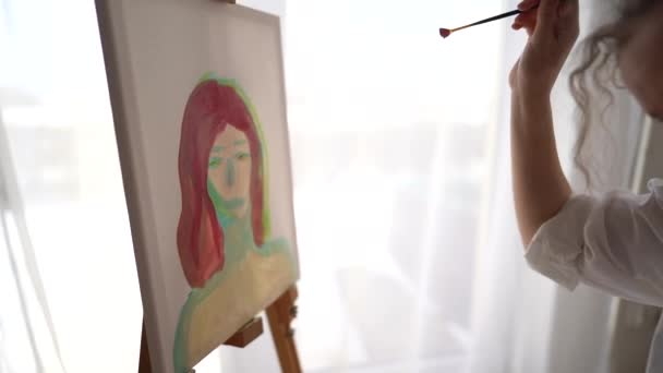キャンバス上の若いアーティストの絵のクローズアップ。少女は筆で女性の肖像画を描く。子供たちが描く。趣味と美術の概念 — ストック動画