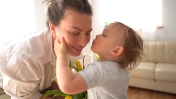 Close portrait of a little cute son kissing his mom congratulating her on March 8 or mothers day — Stock Video