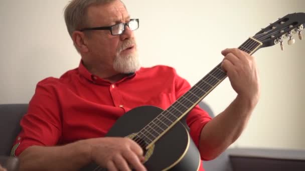 Κοντινό πορτραίτο ηλικιωμένου ζευγαριού που απολαμβάνει να παίζει κιθάρα στο σπίτι του. Έχουν ένα χαμογελαστό και χαρούμενο πρόσωπο. Έννοια δραστηριότητας της ηλικίας συνταξιοδότησης — Αρχείο Βίντεο