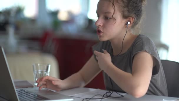 Uczę się online. Uważna dziewczyna ze słuchawkami używa laptopa do nauki w Internecie, odrabiania lekcji na odległość podczas okresu kwarantanny. E-edukacja na odległość, edukacja domowa — Wideo stockowe