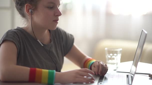 Gekruld tiener meisje maakt huiswerk in de buurt van de laptop. Online leren, afstandsonderwijs, thuisonderwijs — Stockvideo