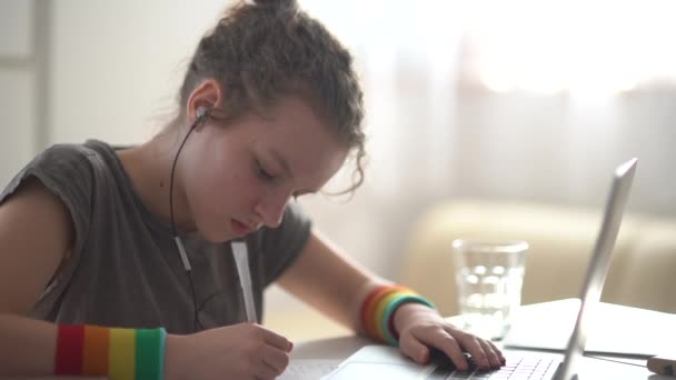 Kędzierzawa nastolatka odrabia lekcje przy laptopie. Uczenie się przez internet, uczenie się na odległość, nauka w domu — Wideo stockowe
