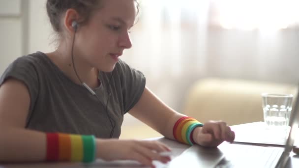 Портрет дівчини з кучерявим волоссям, що має відеодзвінок за допомогою ноутбука та навушників. Домашнє навчання, дистанційна зайнятість, концепція електронного навчання — стокове відео