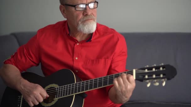Portrait d'un pensionné apprenant à jouer de la guitare. Vieillesse heureuse, passe-temps préféré — Video