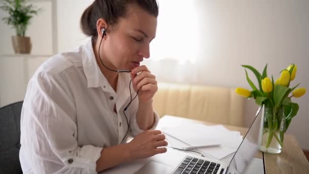 Szczęśliwa młoda kobieta biznesu nosi słuchawki rozmowy z kamery internetowej podejmowania odległość online wideokonferencji. Nauczycielka Internetu na odległej czacie pracująca w domu. Koncepcja telepracy — Wideo stockowe