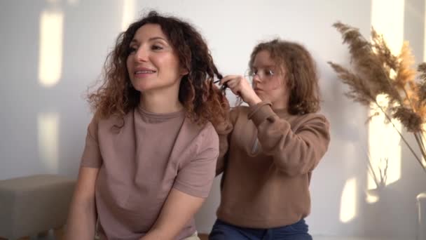 Daughter braids moms braids. Indoor portrait of happy mother and daughter spend weekend together. Mothers Day — Vídeo de Stock