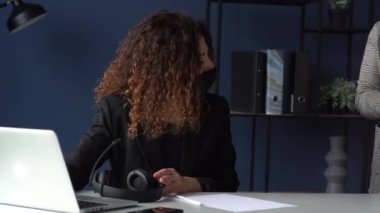Kadınlar ofiste koruyucu maskeler takarlar. Yeni normallik. İş kadını, patrona imzalanması için belgeler getirdi. İş fikirleri imzalamak ve planlamak