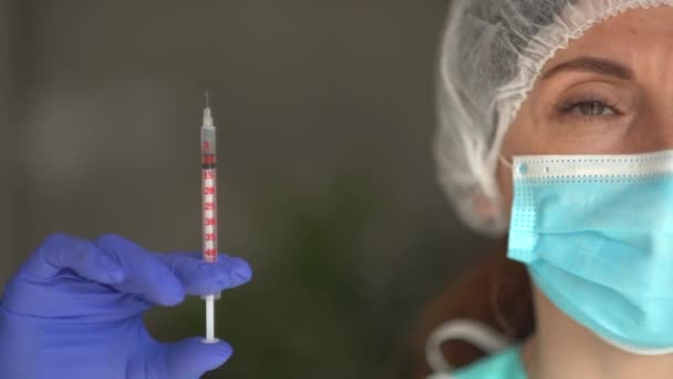 Maske ve eldiven takan bir hemşirenin portresi şırınga taşıyor, virüslere karşı muhtemel tedaviler ve hastalıklar. Sağlık hizmeti enjeksiyon kavramı — Stok video