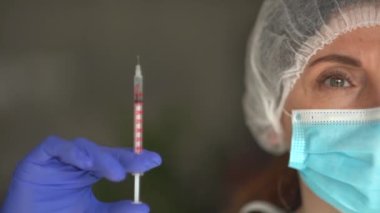 Yüz maskeli genç bir kadın, doktor ya da hemşire elinde şırınga, virüslere karşı muhtemel tedaviler ve hastalıklar var. Sağlık hizmeti enjeksiyon kavramı