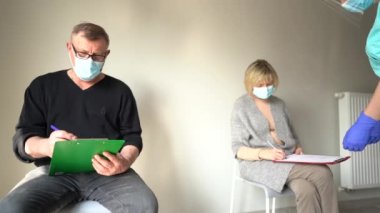Hemşire, emeklilerin aşı öncesi kontrol listelerini bir hastanede ya da bakımevinde tamamlamalarına yardımcı olur. Risk grupları, aşının ilk aşaması. Nüfusun covid-19 Coronavirus 'a karşı bağışıklığı