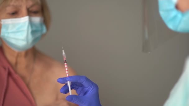 Närbild av en äldre pensionär och en spruta med en dos vaccin förbereder sig en mogen kvinna för att få ett vaccin. Begreppet Codid-19 vaccination — Stockvideo