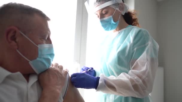 Starszy mężczyzna otrzymuje szczepionkę przeciw koronawirusowi. Przyjazna pielęgniarka szczepiąca starszego pacjenta przeciwko grypie, grypie, zapaleniu płuc lub koronawirusowi — Wideo stockowe