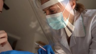 Nüfusun covid-19 koronavirüse karşı aşılanması. Koruyucu maskeli ve kalkanlı yakın plan doktor olgun kadınlara aşı enjekte ediyor.