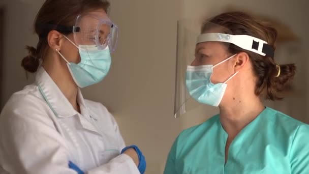 Женщины-врачи встречаются в больничном коридоре, обсуждают результаты анализов, надевают хирургическую маску во время пандемии коронавируса — стоковое видео