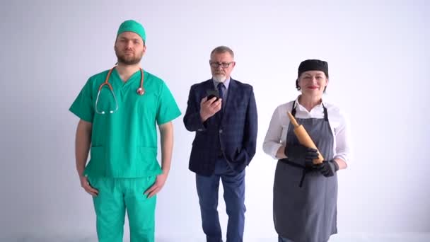 Porträtt av tre personer med olika yrken och yrken som står sida vid sida på vit bakgrund. Affärsman, läkare och kock i uniform — Stockvideo