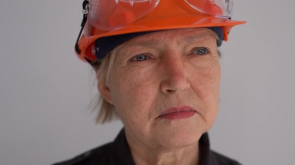 Close-up portret van een volwassen vrouw bouwer in een helm. Het beroep is civiel ingenieur of architect. Serieuze professionele vrouw — Stockvideo