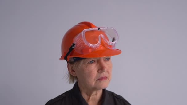 Concepto inmobiliario. Anciana ingeniera constructora en un casco naranja con una carpeta en la mano grita en un megáfono. Publicidad importante, actividad profesional — Vídeo de stock