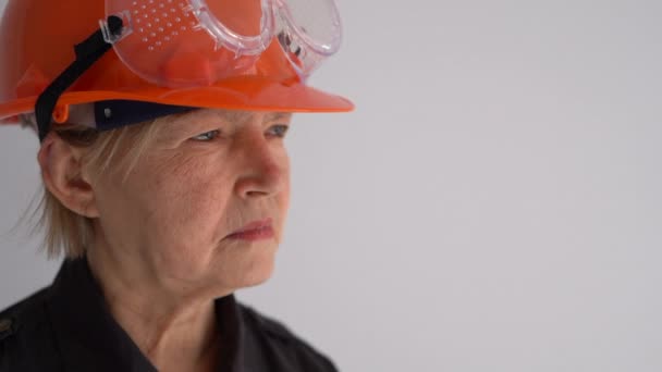 Retrato de uma mulher idosa arquiteta com um megafone e em um capacete protetor. Gritos no alto-falante — Vídeo de Stock