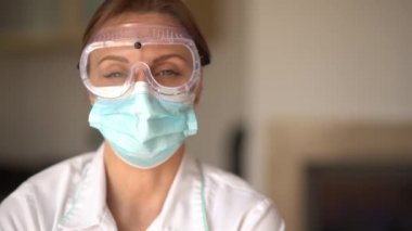 Koruyucu kalkan ve maske takan yorgun bir kadın terapistin portresi. İşten sonra doktor, yakın portre.