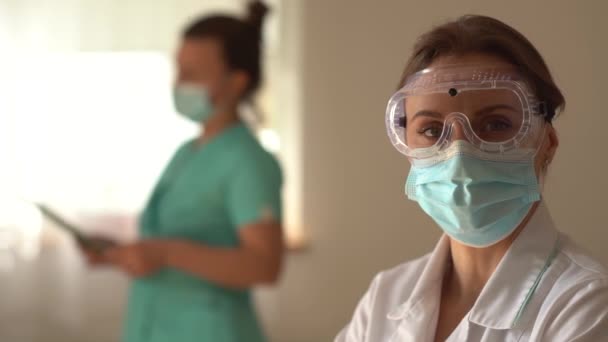 Retrato de una terapeuta cansada con escudo protector y máscara. Médico después del trabajo, retrato cercano — Vídeos de Stock