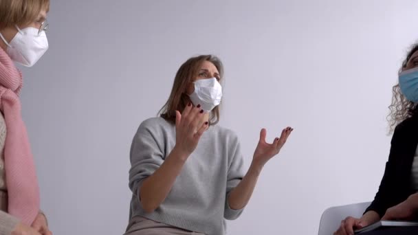 Uma mulher mascarada fala sobre uma experiência traumática na infância durante a terapia de grupo com um psicólogo. Pessoas mascaradas no escritório de psicólogos — Vídeo de Stock