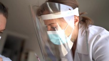 Koruyucu maske ve kalkan takan kadın bir doktorun yakın plan çekiminde covid-19 koronavirüs aşısı yapılır. Aşılama kavramı