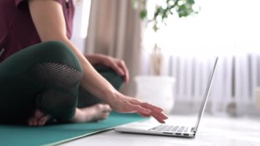 Teknoloji, iletişim, uzak öğrenme ve sosyal uzaklık. Tanınmayan kız dizüstü bilgisayarda kablosuz yüksek hızlı internet bağlantısı kullanıyor, yoga eğitmenini online olarak izliyor, paspasın üzerinde oturuyor.