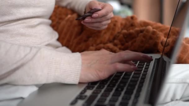 Primer plano de las manos femeninas entrar en el número de tarjeta en línea utilizando un ordenador portátil. Mujer utiliza el ordenador portátil para pagar facturas desde casa, banca en línea — Vídeos de Stock