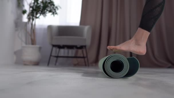Крупним планом нога і рука невпізнаваної жінки, що розгортає йога килимок для фізичної активності вдома. Залишайтеся вдома концепція, психічне здоров'я та медитація — стокове відео