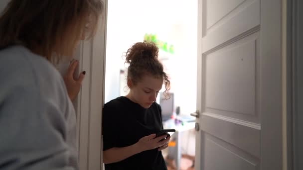 A mother tries to talk to her teenage daughter. The girl closes the door of her room in front of her mother — Stock video