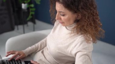 Close up portrait of a beautiful curly woman with a laptop and a credit card in her hands. The girl is shopping online. Online shopping from home, stay home