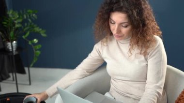 Woman working in home office during coronavirus pandemic, using a laptop computer and drinking coffee, woman working remotely from home