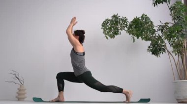 Woman yoga instructor shows classic exercises. Warrior pose, practicing assanas
