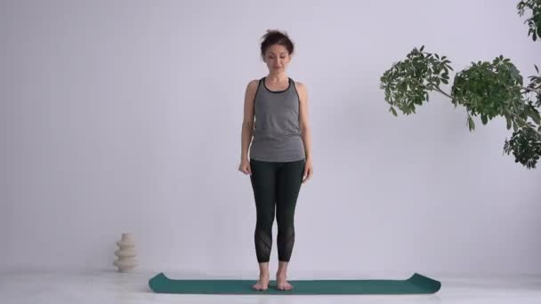 Yoga Assana training. Balance exercises. An attractive adult girl performs exercises while standing barefoot on a mat and loses her balance — Stockvideo